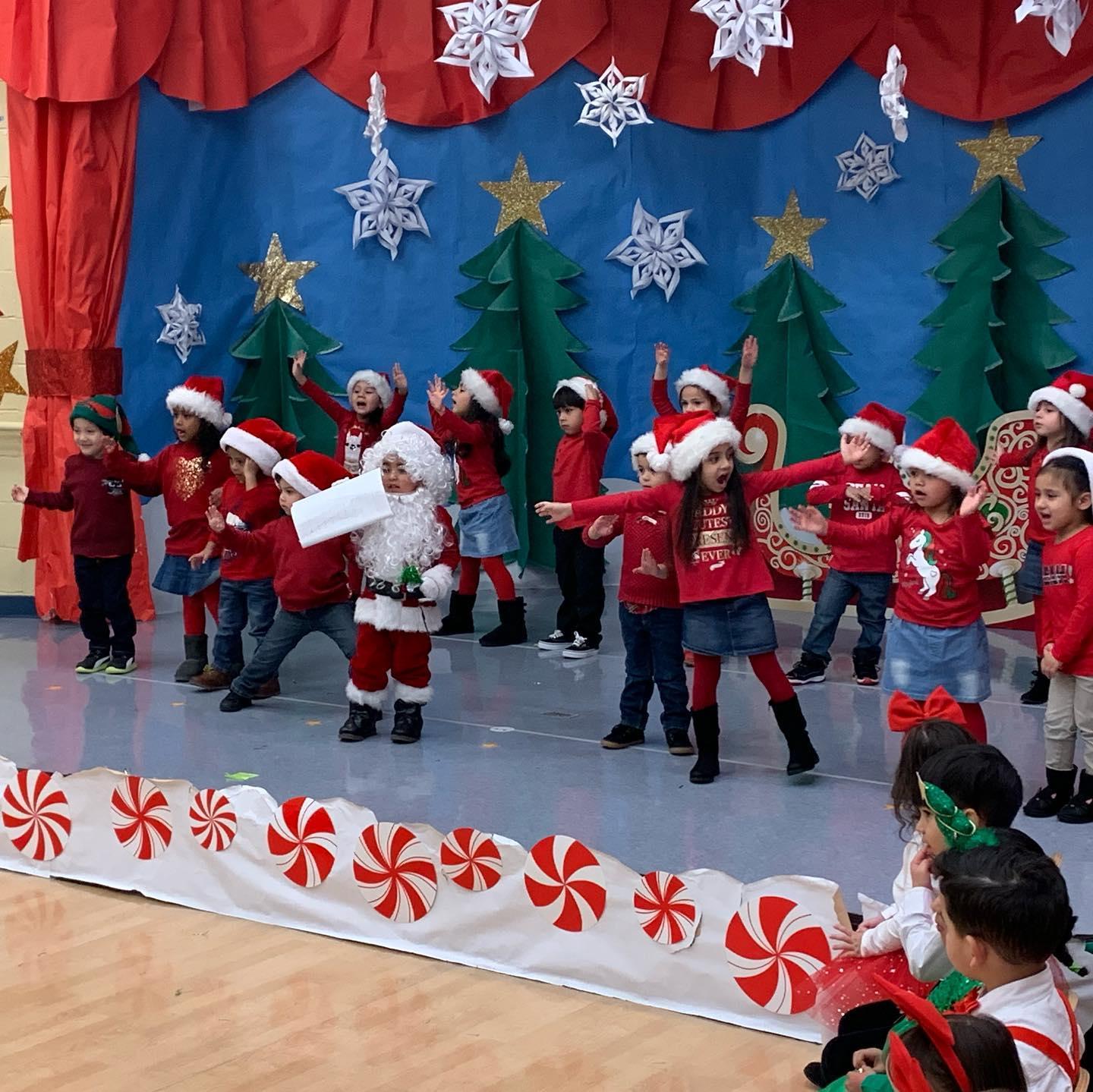 children on stage dressed as Santa and his helpers wearing red with red hats