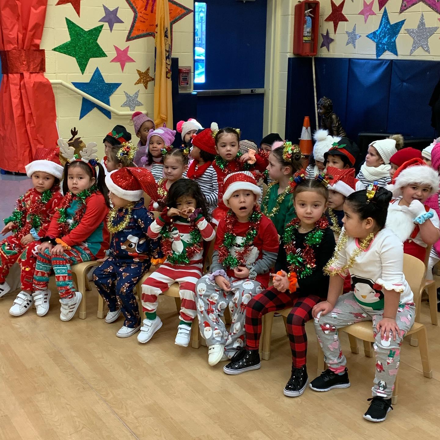 children seated and dressed in assorted Christmas outfits wearing sparkly garland