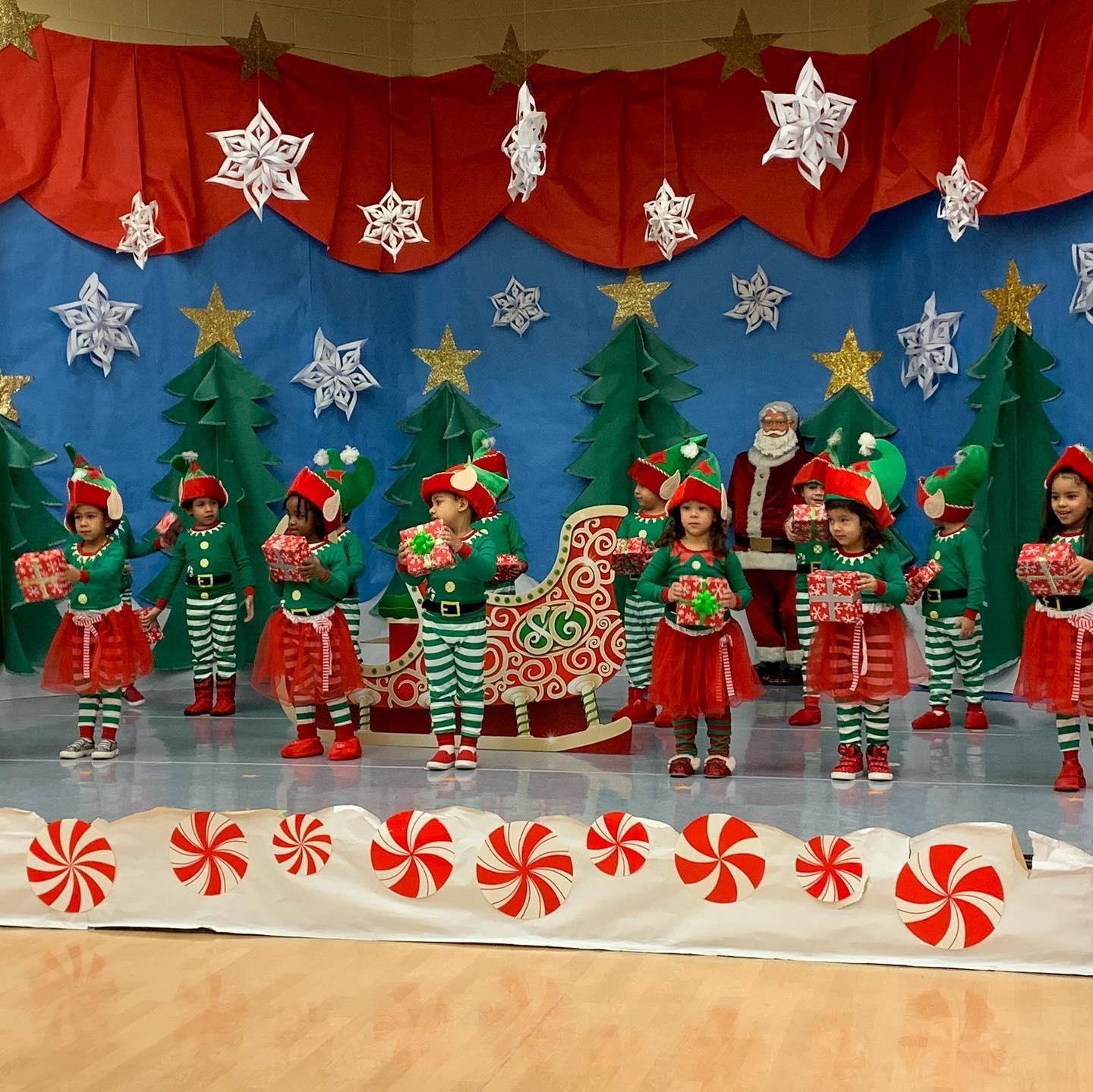 children dressed as elves on stage singing