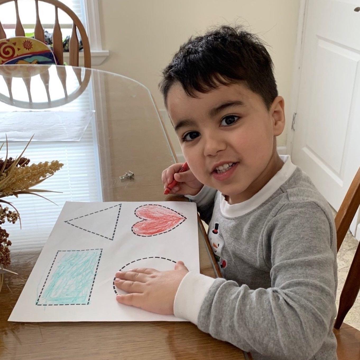 boy coloring his shape activity sheet