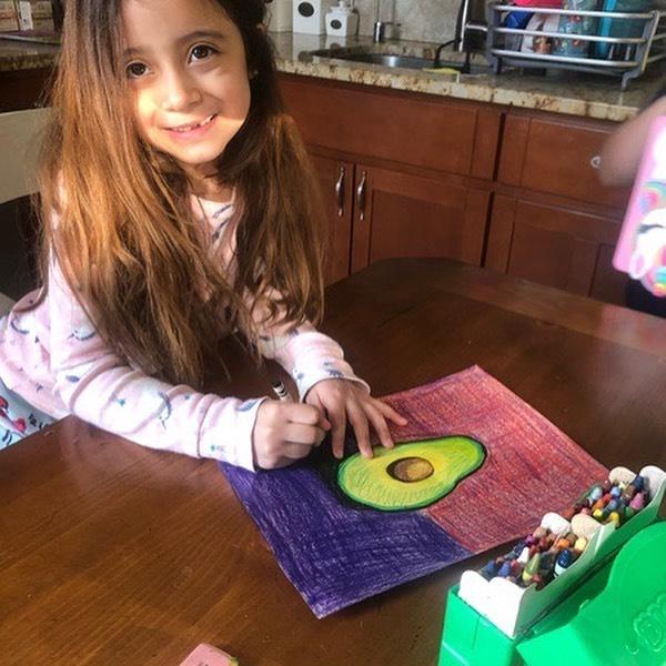 girl drawing an avocado on the kitchen table
