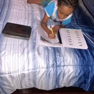 boy doing his work on the bed